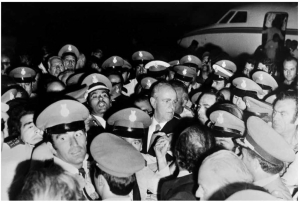 24 Ιουλίου 1974, Αθήνα. Ο Κωνσταντίνος Καραμανλής, περιβαλλόμενος από αστυνομικούς, έχει μόλις αποβιβαστεί από το αεροπλάνο που τον μετέφερε από το Παρίσι. Η χούντα είναι παρελθόν, αρχίζει ο κύκλος της μεταπολίτευσης.  