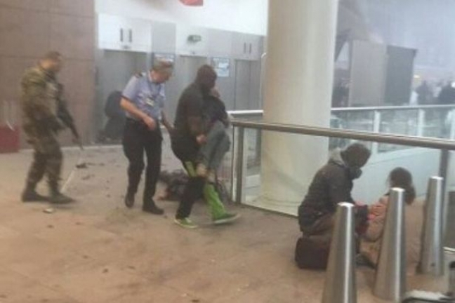 Αεροδρόμιο Βρυξελλών, 22 Μαρτίου, περίπου 9 το πρωί ώρα Ελλάδος. Αστυνομικοί και υπάλληλοι του αεροδρομίου προσπαθούν να μεταφέρουν τραυματίες από την αίθουσα όπου έγινε η φονική τρομοκρατική έκρηξη.