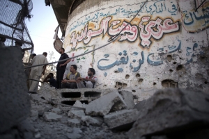 Παλαιστίνιοι στηρίζονται στον τοίχο γκρεμισμένου σπιτιού, στην πόλη Σουιαγιέ, που βρίσκεται στη λωρίδα της  Γάζας, έπειτα από δίωρο βομβαρδισμό ισραηλινών αεροπλάνων, στις 23 Ιουλίου 2014.