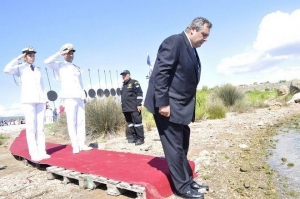 O υπουργός Εθνικής Αμύνης Πάνος Καμμένος στη σεμνή τελετή εις ανάμνησιν της νικηφόρου ναυμαχίας της Σαλαμίνος κατά των βαρβάρων Περσών. Το στέλεχος της συγκυβέρνησης ΣΥΡΙΖα-ΑΝΕΛ Νο2 πατά σε λερό κόκκινο χαλί στηριγμένο σε παλέτες, τιμές αποδίδουν δυο ναύτες αμφοτέρων των φύλων και ένας ακόμα με στολή στρατιωτική, ενώ στο βάθος διακρίνονται 11 σάρισες μπηγμένες στο έδαφος. Από τη φωτογραφία απουσιάζουν οι καραγκούνες με σημαίες συμμάχων χωρών, όπως οι ΗΠΑ ή η Κούβα, ο παππούλης που διάβασε τρισάγιο (εις μνήμην του δωδεκαθεϊστού Θεμιστοκλέους), οι αμαζόνες και ο κ. Τραγάκης, της ΝΔ, που πήγε εκεί για να τονίσει την εθνική ομοψυχία στο κιτς.