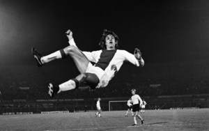 O Γιόχαν Κρόιφ ίπταται, σε ένα ποδοσφαιρικό στιγμιότυπο από τη μακρινή δεκαετία του 1970, όταν ο ολλανδός ποδοσφαιριστής ήταν το αστέρι του Άγιαξ και φορούσε τη φανέλα με το νούμερο 14.