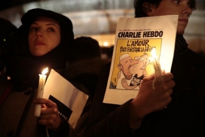 To Παρίσι δεν φοβάται. Διαδηλώτρια κρατά πλακάτ με εξώφυλλο του περιοδικού Charlie Hebdo, στη συγκέντρωση στην Place De La Republique, αμέσως μετά το δολοφονικό χτύπημα ισλαμοφασιστών εξτρεμιστών στα γραφεία του περιοδικού. 