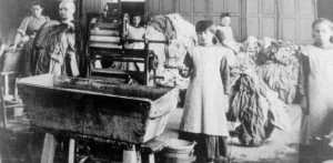 Εικόνα από ένα πλυσταριό της Μαγδαληνής στην Ιρλανδία, περίπου δεκαετία του 1920. Υποτίθεται, ήταν μια απασχόληση στο πλαίσιο της φιλανθρωπικής λειτουργίας μοναστηριών, στην οποία απασχολούνταν νεαρά κορίτσια (κακοποιημένες, ανύπαντρες έγκυοι που τις έδιωχναν οι εραστές ή η οικογένεια, παραβατικές) για βοήθεια και επανένταξη στην κοινωνία. Τα κορίτσια αυτά, όμως, εργάζονταν στα πλυσταριά: έπλεναν στη σκάφη, συνεχώς, ρούχα υπό άθλιες συνθήκες, πολλές φορές για χρόνια, χωρίς αμοιβή, υποχρεωτικά, χωρίς να είναι ελεύθερα να φύγουν, ενώ παράλληλα έπρεπε να εργάζονται για το μοναστήρι και να υπηρετούν τις καλόγριες. Το τελευταίο από τα πλυντήρια της ντροπής έκλεισε μόλις το 1996. Τρία χρόνια νωρίτερα ήρθαν στο φως 155 ανώνυμοι τάφοι κρατουμένων γυναικών και παιδιών. Πολύ πρόσφατα, ο ιρλανδός πρωθυπουργός αποκάλεσε τα πλυσταριά της Μαγδαληνής «ντροπή της Ιρλανδίας». Η φωτογραφία προέρχεται από το βιβλίο του F. Finnegan, Do Penance or Perish. A Study of Magdalen Asylums in Ireland, Congrave Press (2001).     