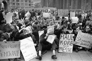 Oκτώβριος 1962. Το περιοδικό Spiegel έχει αμφισβητήσει την πολιτική επανεξοπλισμού της Γερμανίας και κυκλοφόρησε με τίτλο «Bedingt abwehrbereit» («Έτοιμοι να αμυνθούμε, αλλά υπό όρους»). Η μετωπική σύγκρουση με τον υπουργό Άμυνας και μετέπειτα πρωθυπουργό της Βαυαρίας, τον υπερσυντηρητικό Φραντς Γιόζεφ Στράους, ήταν αναπόφευκτη. Η αστυνομία κατηγόρησε τους δημοσιογράφους για «αποκάλυψη κρατικού απορρήτου», εισέβαλε στα γραφεία της σύνταξης και συνέλαβε τον ιδρυτή και εκδότη του περιοδικού, Ρούντολφ Αουγκστάιν, και πολλούς συνεργάτες του, που οδηγήθηκαν στη φυλακή με την κατηγορία της «προδοσίας». Αλλά οι πολίτες αντέδρασαν με ογκώδεις διαδηλώσεις, ζητώντας την ελευθερία του Τύπου – όπως αυτή της φωτογραφίας, που δείχνει φοιτητική διαδήλωση στη Φρανκφούρτη. Προκλήθηκε κυβερνητική κρίση και ο καγκελάριος Κόνραντ Αντενάουερ αναγκάστηκε να απολύσει τον Στράους, ενώ το Spiegel επέστρεψε θριαμβευτικά στα περίπτερα εδραιώνοντας τη φήμη του ως το «βαρύ πυροβολικό της δημοκρατίας». Ήταν, βέβαια, άλλοι καιροί. 