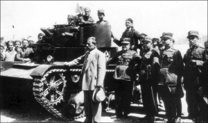 Ο Γεώργιος Κονδύλης, Υπουργός Στρατιωτικών που κατέστειλε το κίνημα του 1935 των φιλελευθέρων, εικονίζεται μπροστά σε ένα τανκ που έχει λευκή σημαία. 