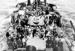 Ναύτες του αντιτορπιλικού Πίνδος, προσκείμενοι στο ΕΑΜ, γιορτάζουν την Πρωτομαγιά του 1944. Η φωτογραφία έχει ληφθεί περίπου ένα μήνα μετά την καταστολή του κινήματος της Μέσης Ανατολής, ενώ το Πίνδος βρισκόταν στο λιμάνι του Οράν. 