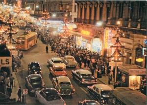 H οδός Σταδίου, στο ύψος των Χαυτείων, όπως την απαθανάτισε τα Χριστούγεννα του 1960 ο φωτογράφος Κώστας Μπαλάφας, καταγράφοντας μια κοινωνία προόδου που αποδείκνυε το δυναμισμό της μέσω των καταναλωτικών της δυνατοτήτων.  