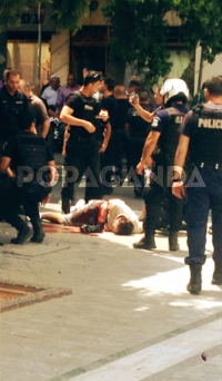 Τετάρτη, 16 Ιουλίου 2015. Ο Μαζιώτης κείτεται τραυματισμένος στο δρόμο, περιστοιχισμένος από αστυνομικούς. Η φωτογραφία τραβήχθηκε από τον Φώτη Βαλλάτο και δημοσιεύθηκε στον ιστότοπο popaganda.gr.