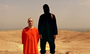 Εικόνα που μετέδωσε το δίκτυο προπαγάνδας του ISIS, από τον δημόσιο αποκεφαλισμό του φωτορεπόρτρ Τζέιμς Φόλεϊ, από μασκοφόρο δολοφόνο, μέλος της εξτρεμιστικής ισλαμιστικής οργάνωσης.