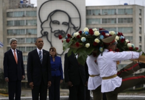 Αβάνα, Κούβα, 21 Μαρτίου 2016. Ο πρόεδρος των ΗΠΑ, Μπαράκ Ομπάμα, περιστοιχισμένος από τον Τζον Κέρρυ και την Ζοζεφίνα Βιντάλ, παρακολουθούν επίσημη τελετή μπροστά από το υπουργείο Εξωτερικών της χώρας, στο κτίριο του οποίου δεσπόζει πορτρέτο του Καμίλο Σιενφουέγος. Ήταν ο τρίτος «barbudo» – ο  γενειοφόρος, που μαζί με τον Κάστρο και τον Τσε Γκεβάρα εισήλθε ελευθερωτής στην Αβάνα, την Πρωτοχρονιά του 1959. Ο Σιενφουέγος, που πολύ γρήγορα διαφώνησε με τον απολυταρχισμό του Κάστρο, εξαφανίστηκε μυστηριωδώς σε ηλικία 27 ετών, σε κυβερνητική μυστική αποστολή με το αεροπλάνο του, τον Οκτώβριο του 1959. Τα ίχνη του δεν βρέθηκαν ποτέ.