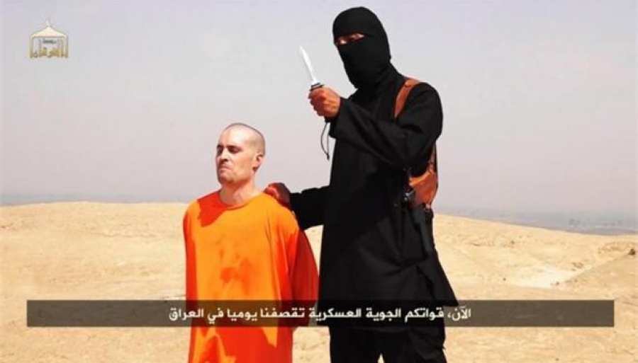 Ο αμερικανός δημοσιογράφος Τζέιμς Φόλεϊ γονατιστός και πάνω του ο μασκοφόρος δολοφόνος του, μέλος του στρατού των ISIS, με το μαχαίρι που θα τον αποκεφαλίσει. Οι στυγνές δολοφονίες και η μετάδοση εικόνων απ&#039; αυτές είναι μέρος της προπαγανδιστικής πρακτικής του Ισλαμικού Κράτους. Η συγκεκριμένη εικόνα προέρχεται από βίντεο που αναρτήθηκε στο διαδίκτυο στις 20 Αυγούστου 2014.