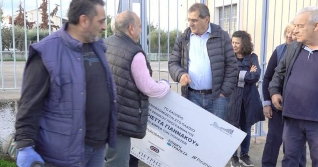 Ο δήμαρχος Πατρέων Κώστας Πελετίδης ξηλώνει πινακίδα από σχολείο της περιοχής του, επειδή έκανε αναφορά στη χρηματοδότηση επισκευών του σχολείου από τις τράπεζες.